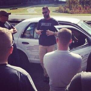 Man standing in front of a car teaching.